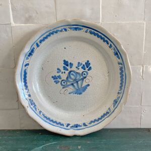 Plat rond en faïence dit cul noir milieu 19è siècle, au décor bleu cobalt peint à la main motif panier fleuri stylisé. Cette pièce typique des faïences rurales françaises du XIXᵉ siècle évoque les productions de Sinceny ou Ger, connues pour leur émail craquelé et leurs décors bleus d’une grande fraîcheur