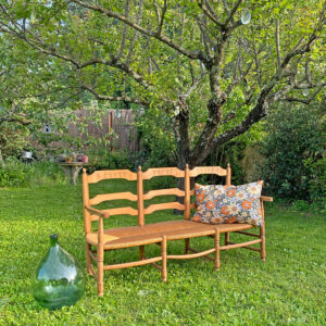 Radassier ou banquette provençale à 3 places, en bois massif avec assise paillée traditionnelle. Rare dossier sculpté représentant une farandole d’Arlésiennes et de gardians, complétée par un tambourinaire sur les dossiers extérieurs, pour les amateurs de Provence, de Camargue et d'Arles conjugués