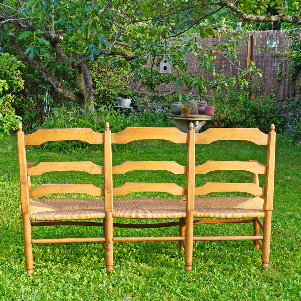 Dos du Radassier ou banquette provençale à 3 places, en bois massif avec assise paillée traditionnelle avec dossier sculpté d'une farandole d’Arlésiennes et de gardians pour les amateurs de Provence, de Camargue et d'Arles conjugués
