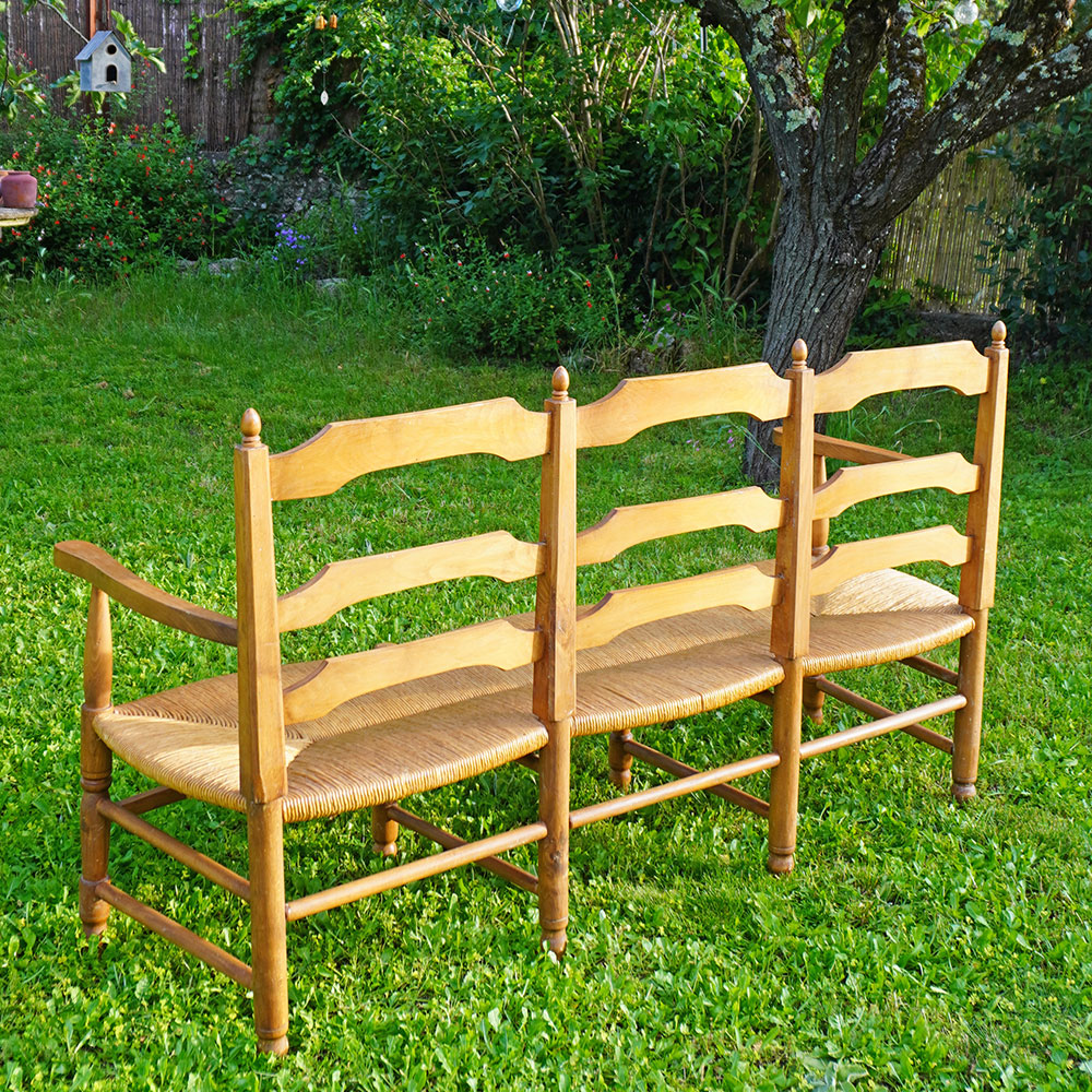 Dos du Radassier ou banquette provençale à 3 places, en bois massif avec assise paillée traditionnelle avec dossier sculpté d'une farandole d’Arlésiennes et de gardians pour les amateurs de Provence, de Camargue et d'Arles conjugués
