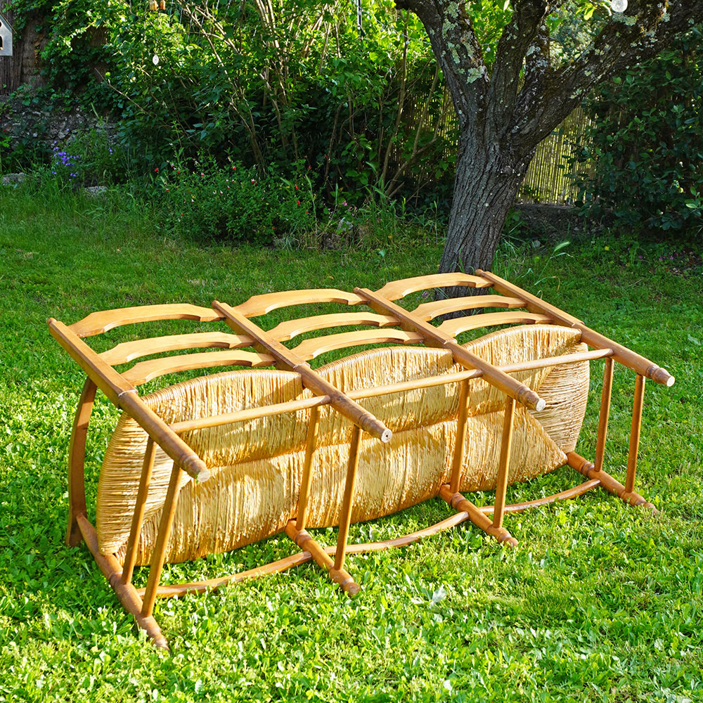 Détail du Radassier ou banquette provençale à 3 places, en bois massif avec assise paillée traditionnelle avec dossier sculpté d'une farandole d’Arlésiennes et de gardians pour les amateurs de Provence, de Camargue et d'Arles conjugués
