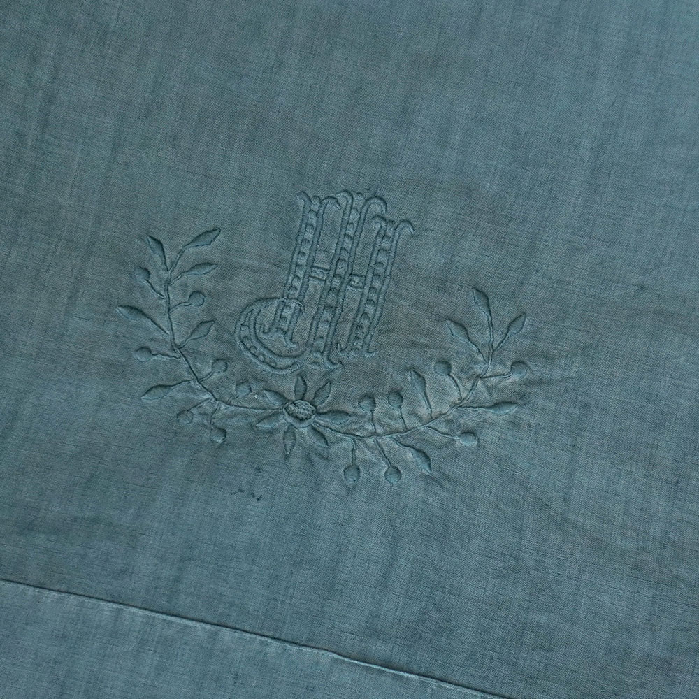 Détail monogramme brodé main HJ sur drap en lin ancien brodé bleu